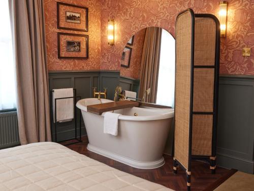 a bathroom with a large tub and a mirror at Dog and Partridge by Greene King Inns in Bury Saint Edmunds