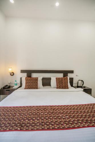 a bedroom with a large white bed with pillows at The Golden Sunrise Hotel in Nainital