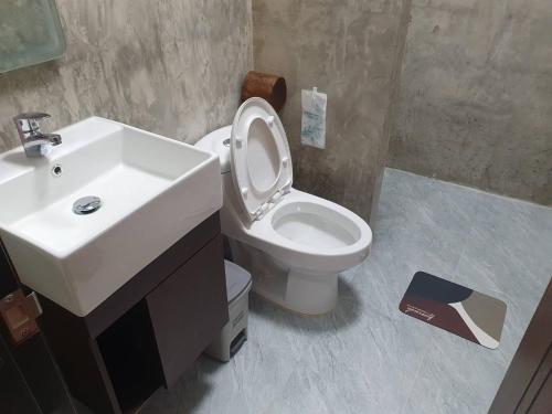 a bathroom with a white sink and a toilet at Kedthawa Homestay เฮือนนาวา in Ban Cho Lae