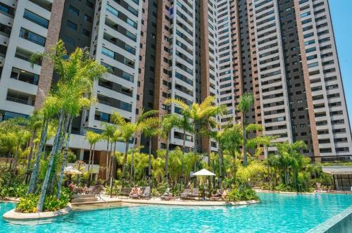 a pool with palm trees in front of tall buildings at Resort, Piscina e Natureza em SP in Sao Paulo