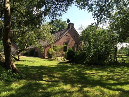 an old brick house with a green yard at Apartment Zus en Zo in Uffelte