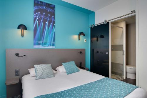 a bedroom with blue walls and a bed with blue pillows at Best Western Hotel Atlantys Zenith Nantes in Saint-Herblain