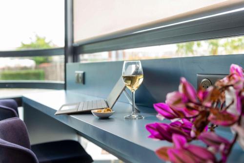 a glass of wine sitting on a table with flowers at Best Western Hotel Atlantys Zenith Nantes in Saint-Herblain