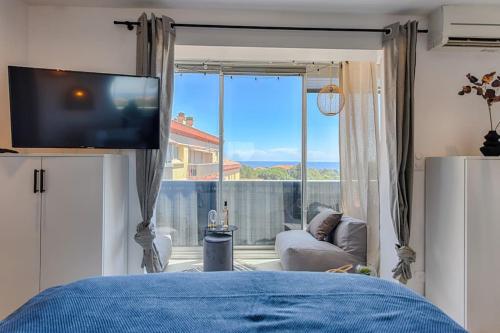 um quarto com uma televisão, um sofá e uma janela em Sea view & spa suite: 3min beach em Fréjus