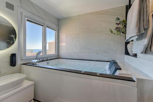 uma casa de banho branca com uma banheira e um lavatório em Sea view & spa suite: 3min beach em Fréjus