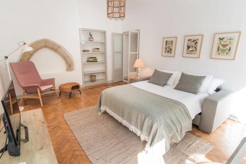 1 dormitorio blanco con 1 cama y 1 silla en Convent's House en Évora