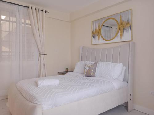 a white bed in a room with a window at Eden Homes in Nakuru