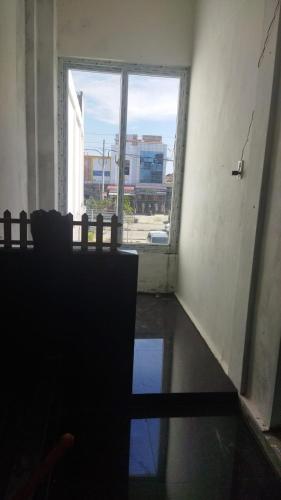 an empty room with a large window and a chair at Ammaro Homestay and Cafe in Meulaboh