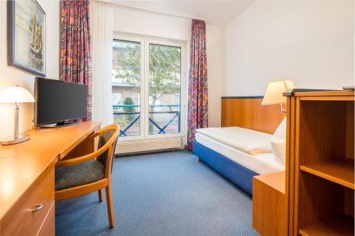 ein Hotelzimmer mit einem Bett, einem Schreibtisch und einem Fenster in der Unterkunft Gästehaus Gelsenkirchen in Norderney