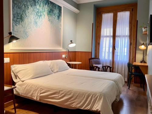 1 dormitorio con 1 cama, mesa y sillas en Hostal La Vera, en Madrid