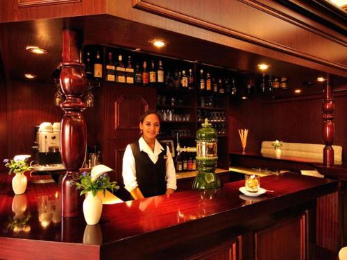 a woman standing behind a bar in a restaurant at Hotel Imperial in Cologne