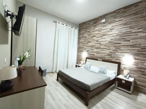 a bedroom with a bed and a brick wall at Domos La Corte Ghibellina in Iglesias