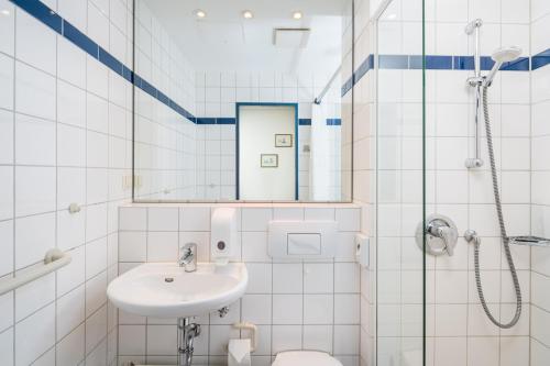 Baño blanco con lavabo y espejo en Gästehaus Gelsenkirchen en Norderney