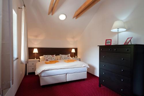 a bedroom with a white bed and a black dresser at Apartmany Hrabovo in Ružomberok