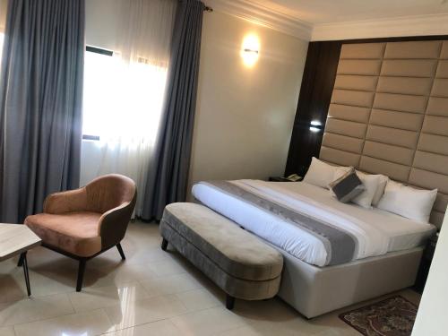 a hotel room with a bed and a chair at Roban Hotels Limited in Enugu