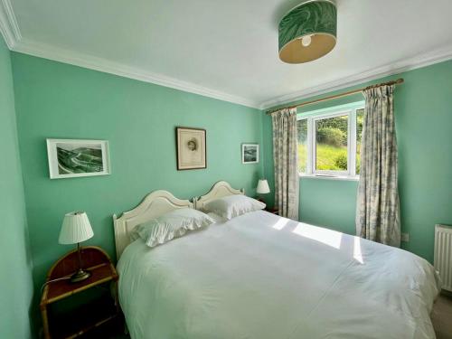 a blue bedroom with a bed and a window at The Pavilion in Long Bredy