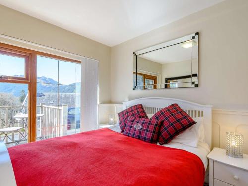 a bedroom with a bed with a red blanket and a mirror at 1 Bed in Arrochar 82648 in Arrochar