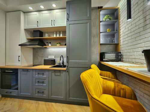 a kitchen with white cabinets and a yellow chair at Akis CityChic Apartment in Cluj-Napoca