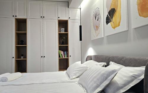 a bedroom with white cabinets and a bed with white pillows at Akis CityChic Apartment in Cluj-Napoca