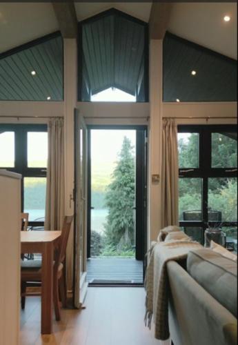 a bedroom with a bed and a table and a large window at Sixpenny Bay in Morenish