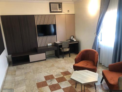 a living room with a tv and a chair and a table at Roban Hotels Limited in Enugu