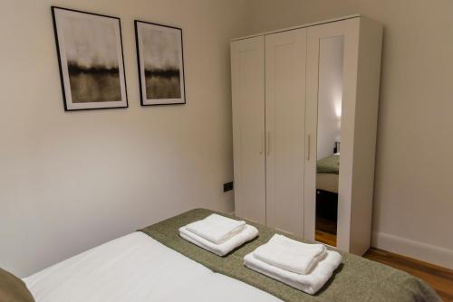 a bedroom with a bed with two white towels at Stylish 3 bedroom flat, free parking in London