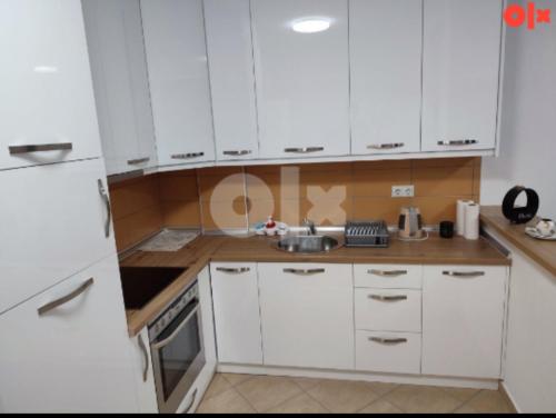 a kitchen with white cabinets and a sink at Atina apartman in Brčko