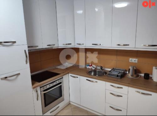 a white kitchen with white cabinets and a sink at Atina apartman in Brčko