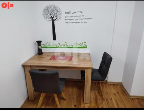 a table with two chairs and a tree on the wall at Atina apartman in Brčko