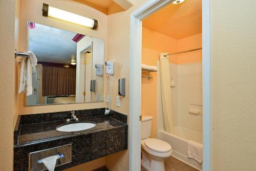 a bathroom with a sink and a toilet and a mirror at Americas Deluxe Inn- Marysville in Marysville