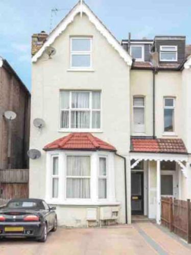 a black car parked in front of a white house at Lovely 1 bedroom flat in quiet Wimbledon in London