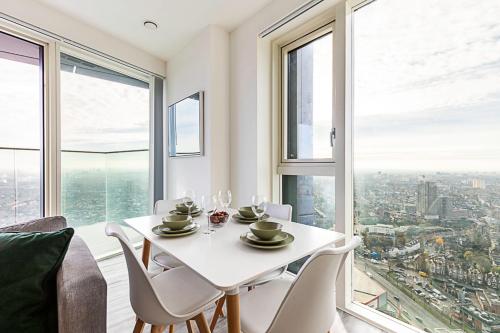 una sala da pranzo con tavolo bianco, sedie e finestre di High Rise Apartment in Acton a Londra