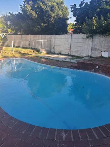 a large blue swimming pool in a yard at Thornton room in Cape Town