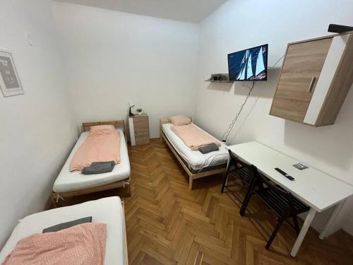 ブルノにあるApartment Vlhkaのベッド2台、デスク、テーブルが備わる客室です。
