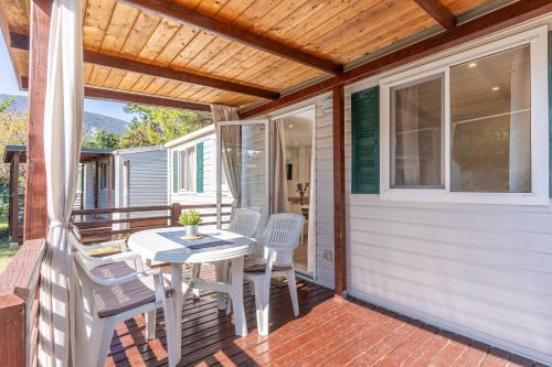 une terrasse couverte avec une table et des chaises. dans l'établissement Mobile Homes Rapoća, à Nerezine