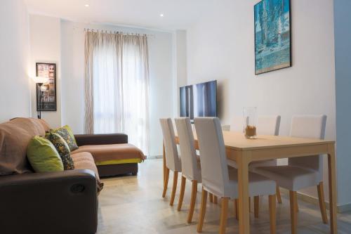 sala de estar con mesa, sillas y sofá en Apartamentos Los Cantaros, en El Puerto de Santa María