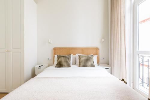 a white bedroom with a large bed with two pillows at Charming Apt Sevilla Center by the bullring by Rodo street in Seville