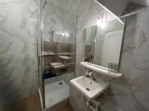 une salle de bain blanche avec un lavabo et une douche dans l'établissement Appartements proches CDG Le Bourget dans maison francilienne typique, au Blanc-Mesnil