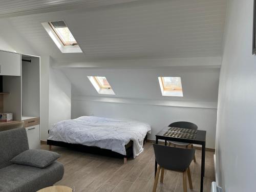 - une chambre avec un lit, une table et des lucarnes dans l'établissement Appartements proches CDG Le Bourget dans maison francilienne typique, au Blanc-Mesnil