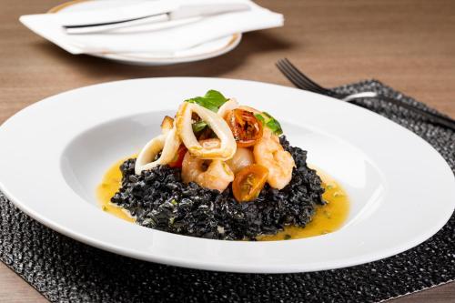 a plate of food with shrimp and black rice at InterContinental Santiago by IHG in Santiago