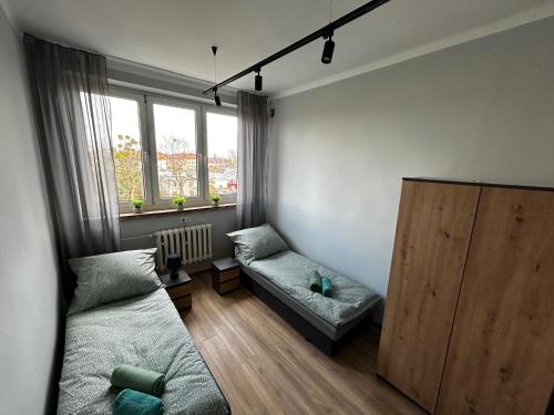 a bedroom with a bed and a couch and a window at CZARNA PERŁA in Wrocław