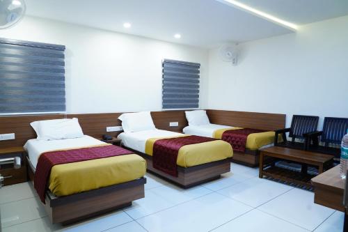 Habitación con 2 camas, mesa y sillas en Rainbow Inn en Munnar