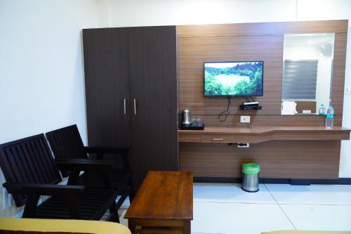 Habitación con escritorio y TV en la pared. en Rainbow Inn en Munnar