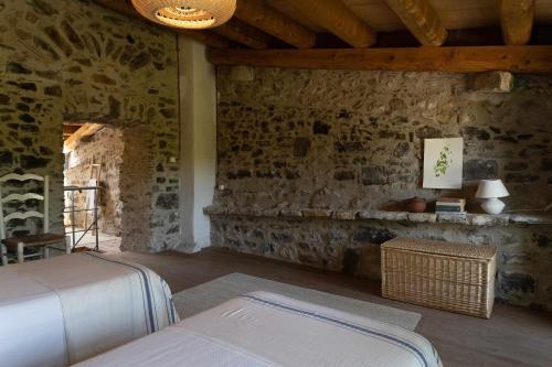 Habitación con pared de piedra, cama y mesa. en Casa Soleil Casa principal y Pajar 11 personas, en Vilopríu