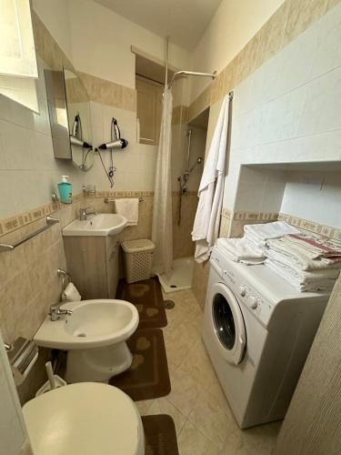 ein Badezimmer mit einer Waschmaschine und einem Waschbecken in der Unterkunft Appartamento in piazzetta in Trecase
