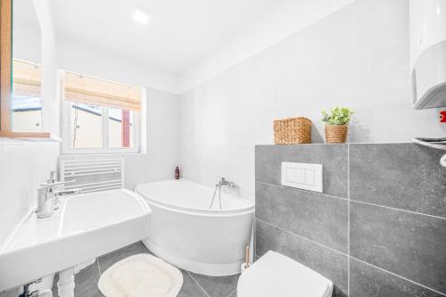 a white bathroom with a tub and a sink at Apartmán Barula in Kašperské Hory