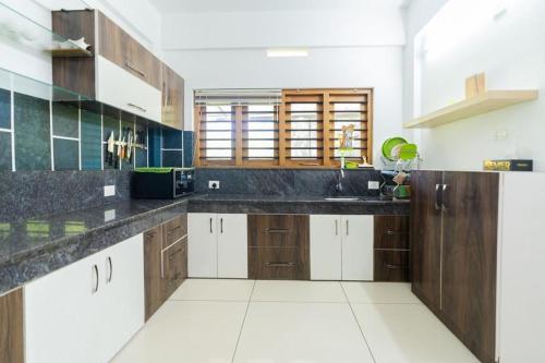 a large kitchen with black counter tops and wooden cabinets at Glendale Hospitality Wayanad in Vythiri