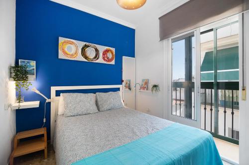 a blue bedroom with a bed and a blue wall at Apartamento La Barca - Chipiona in Chipiona