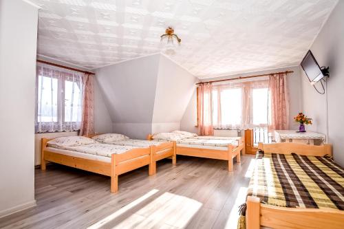 a room with three beds and a tv and windows at Dom Wypoczynkowy u Ewy in Biały Dunajec