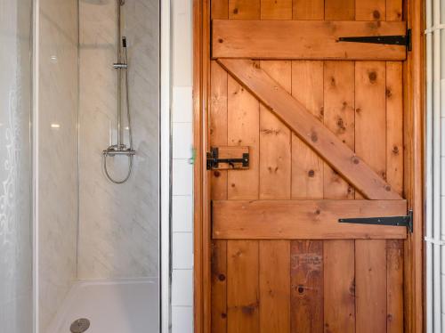 a bathroom with a wooden door and a shower at 1 bed in Brynteg 87362 in Llanwenog